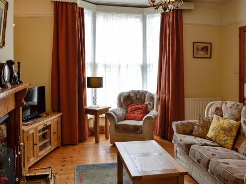 a living room with a couch and chairs and a tv at Ty Nain in Tywyn