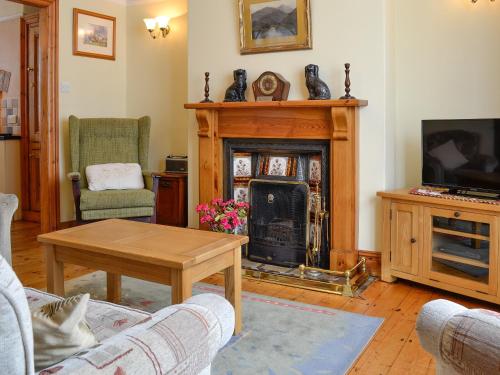 a living room with a fireplace and a table at Ty Nain in Tywyn