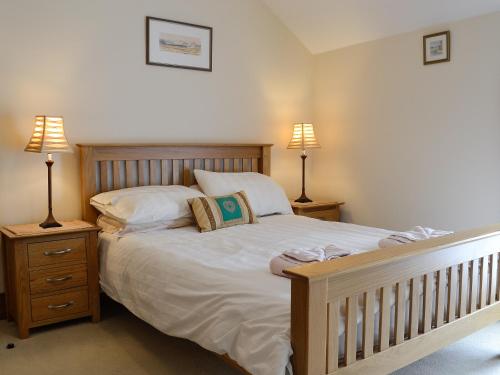 a bedroom with a large bed with two lamps at Ty Nain in Tywyn