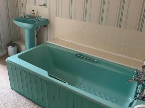 a bathroom with a green tub and a sink at Midships in Instow