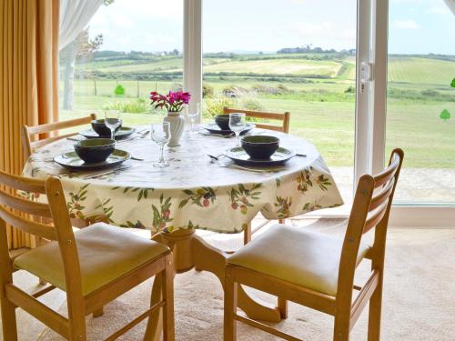 a dining room table with chairs and a table and a window at Cliff End in Freshwater