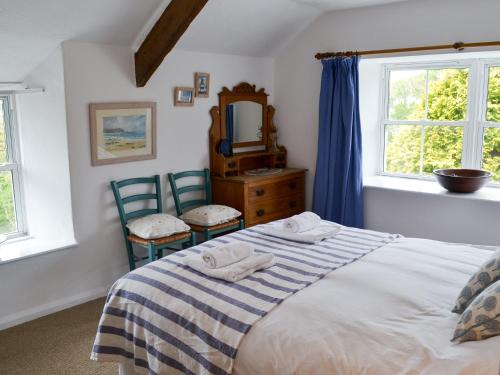 a bedroom with a bed and two chairs and a mirror at Trecarian in Port Isaac