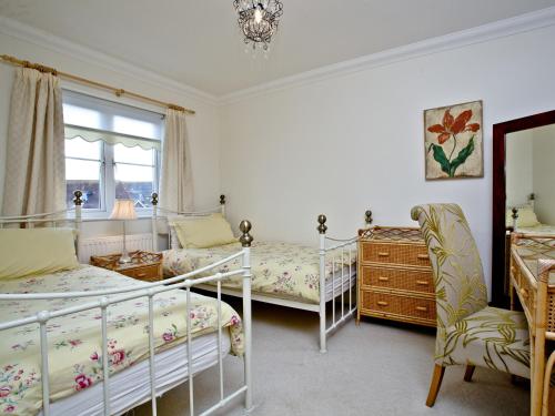a bedroom with two beds and a dresser at Cormorant View in Weymouth