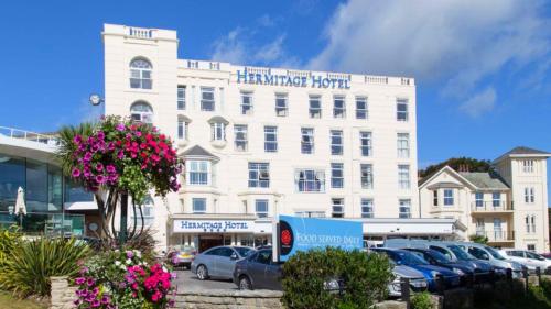 un gran edificio blanco con coches estacionados frente a él en The Hermitage Hotel - OCEANA COLLECTION, en Bournemouth