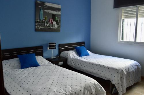 two beds in a room with blue walls at Villa Rosa in Canillas de Albaida