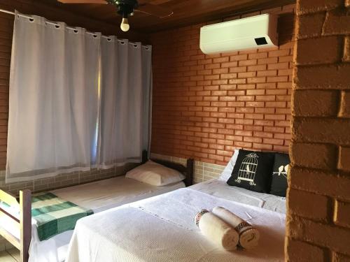 a bedroom with a bed and a brick wall at Pousada Nativo's in Nova Almeida