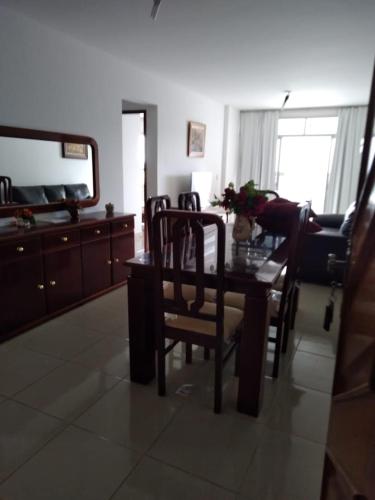 sala de estar con mesa, sillas y espejo en apartamento em Guarapari, en Guarapari