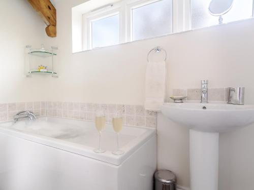 a white bathroom with a sink and a tub and a toilet at The Old Dairy in Cam