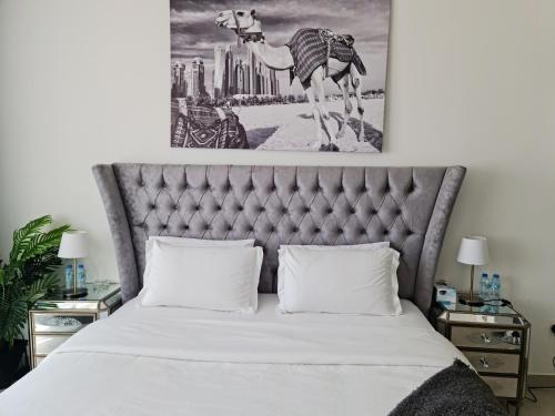 a bedroom with a bed with a camel painting on the wall at Cozy Furnished Studio in Abu Dhabi
