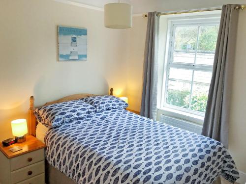 a bedroom with a blue and white bed and a window at Harbour Watch in Charlestown