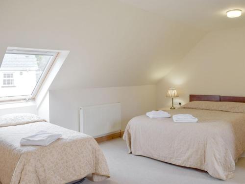 two beds in a white room with a window at Pentre Cottage in Ferryside