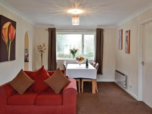 a living room with a red couch and a table at Trebah - B5623 in Saint Cleer