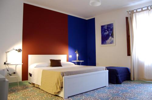 a bedroom with a bed and a blue wall at Casa Helios in Castellammare del Golfo