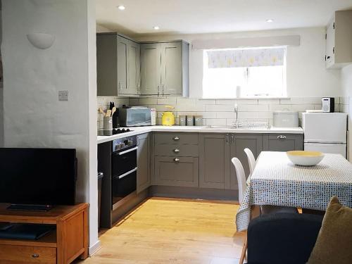 a kitchen with gray cabinets and a table with a tablecloth on it at Oak Barn in Porthtowan