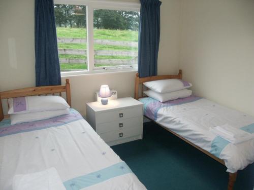 two twin beds in a room with a window at Fell Croft in Pooley Bridge