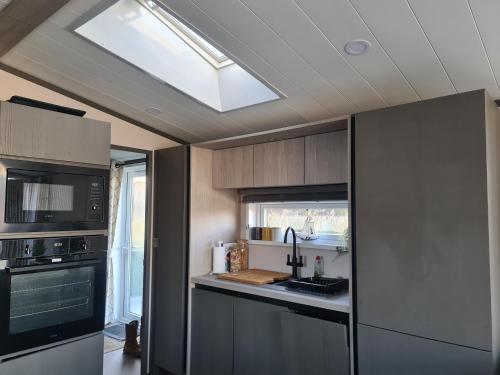 a kitchen with a ceiling with a skylight at Mawgan Pads Lazy Days Lodge in Mawgan Porth