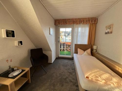 1 dormitorio con cama, escritorio y ventana en Sevda's Hotel Garni Weinforth, en Willingen