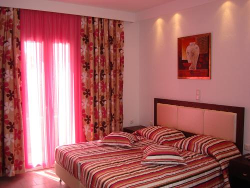 a bedroom with a large bed with red curtains at Elena Studios & Suites in Ornos