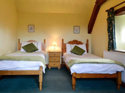 a bedroom with two beds and a lamp on a table at The Coach House in Llanasa