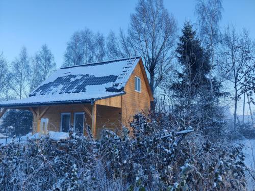 a small wooden house with snow on the roof at Osada Karszewo, sauna bania, ryby in Karszewo