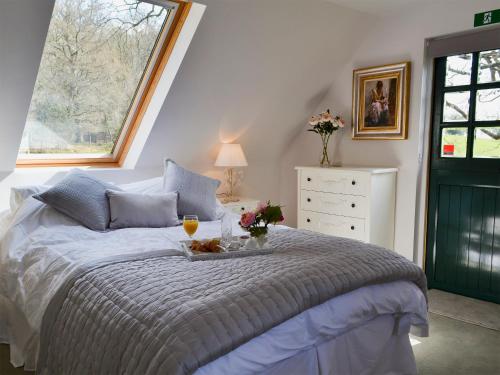 a bedroom with a bed with a tray of food and a window at Horncombe Stables in West Hoathley