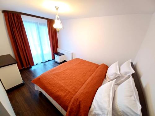 a bedroom with a bed with an orange blanket at Conacul Munții Bucovinei in Câmpulung Moldovenesc