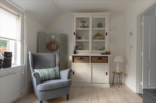 a living room with a chair and a cabinet at Villa Grace in Dalfsen