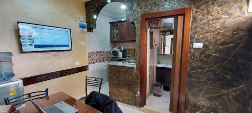 uma cozinha com uma mesa e uma televisão na parede em Khirfan Crown Houses -downtown em Amã