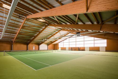 a tennis court in a large building with windows at Thöles Hotel Bücken in Bücken
