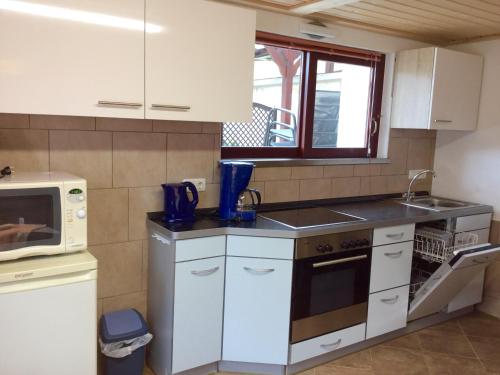 a kitchen with white cabinets and a sink and a microwave at Ferienwohnung Gisela Winkler in Rathen