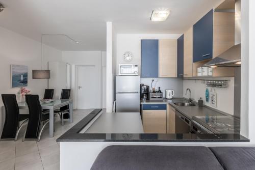 een keuken met blauwe kasten en een tafel met stoelen bij Sundowners Apartment, 52qm, double & single bed, 10 min from Old Town of Split in Split
