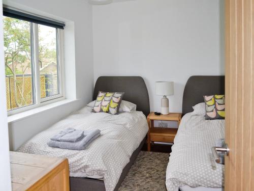 a bedroom with two beds and a window at The Seashells in Brancaster