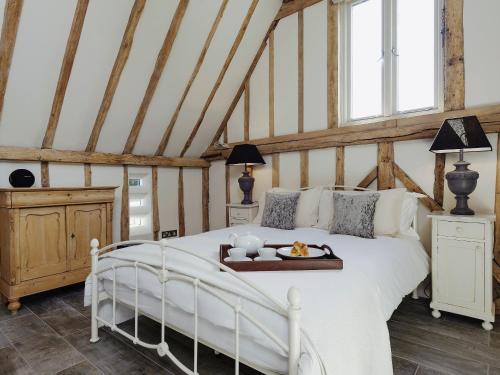 a bedroom with a white bed with a tray on it at Tatters Barn in Bradwell