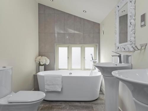 een witte badkamer met een bad en een wastafel bij Tatters Barn in Bradwell