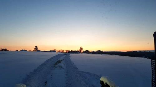 a snowy road in a field with the sunset in the background at CHALUPA KOTÁR - 7 míst za 1 cenu in Haluzice