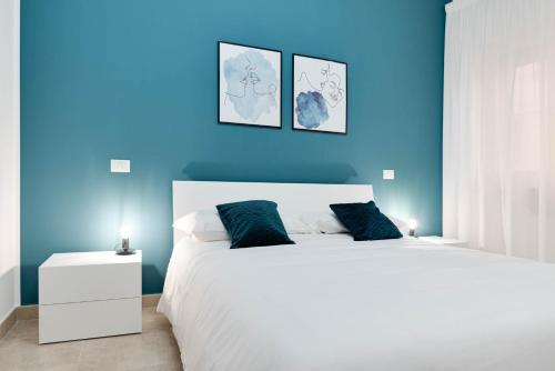 a blue bedroom with a large white bed with blue walls at Jòia Holiday Home in Crotone