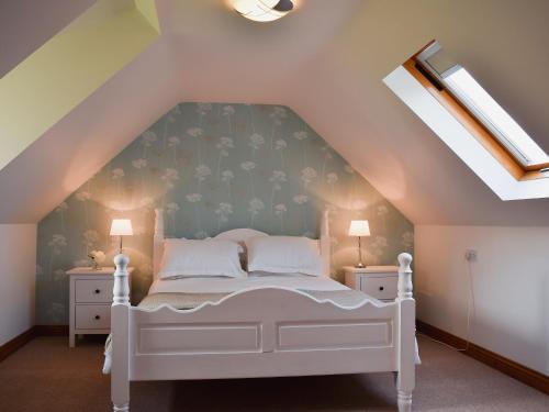 um quarto com uma cama branca num sótão em Millers Rest em Willingham