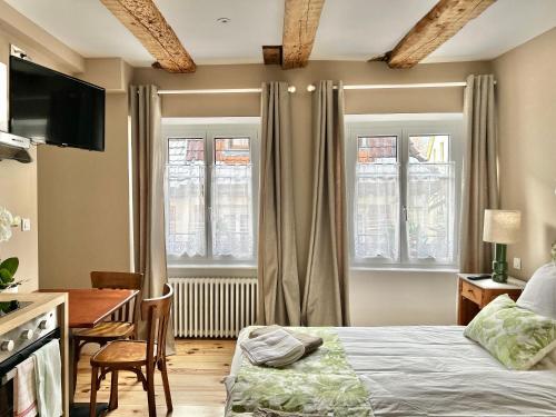 a bedroom with a bed and a desk and windows at Hostellerie Alsacienne in Masevaux