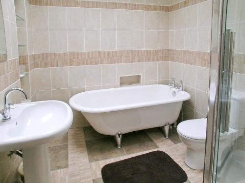 a bathroom with a tub and a toilet and a sink at The Dairy in Delph