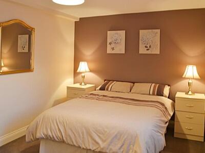 a bedroom with a bed and two night stands with lamps at Willow Cottage in Hadston