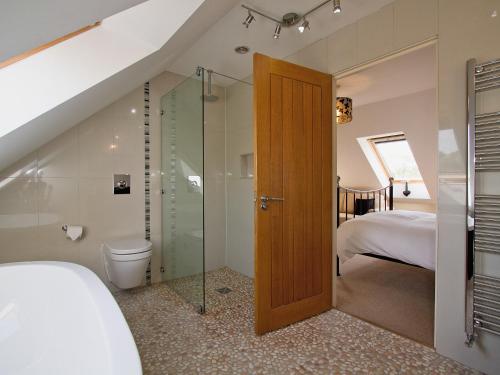 een badkamer met een douche, een toilet en een bed bij Shoreline Penthouse - 27142 in Alnmouth