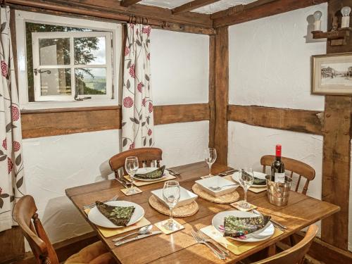 una mesa de madera con platos y copas de vino. en Pen Copi, en Trefeglwys