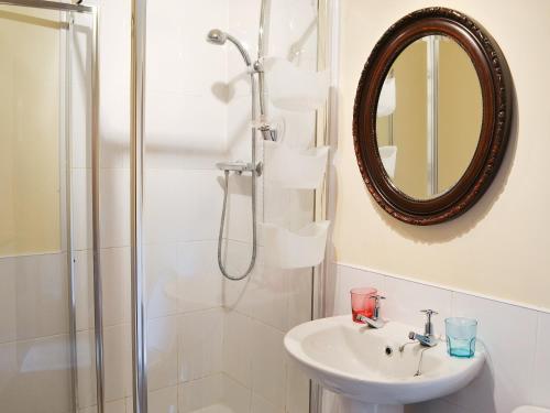 a bathroom with a shower and a sink and a mirror at Piglet Cottage in Elsdon