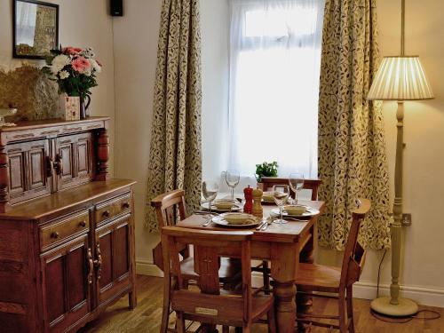 uma sala de jantar com uma mesa e uma janela em Jackdaw Cottage em Baycliff