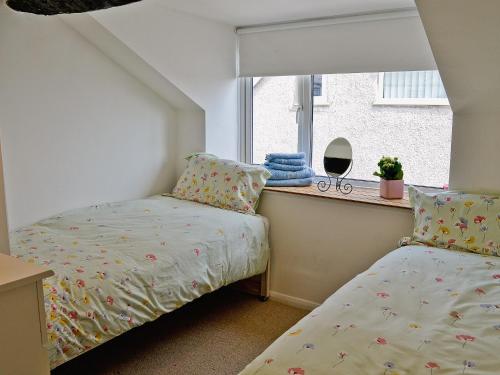 um quarto com 2 camas e uma janela em Jackdaw Cottage em Baycliff