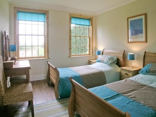 a bedroom with two beds and a desk and two windows at Rascal Wood in Holme upon Spalding Moor