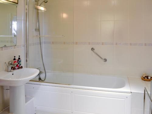 a white bathroom with a shower and a sink at 12 Maritime House in West Bay