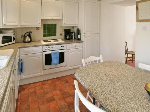 una cocina con armarios blancos y una mesa con encimera. en Middledrift Cottage, en Brora