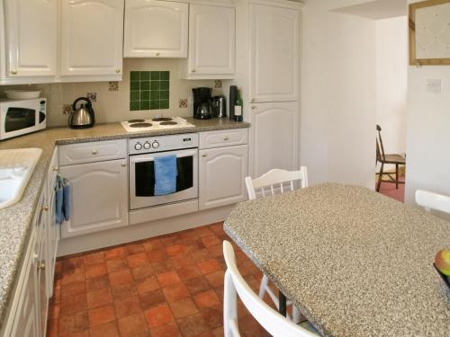 a kitchen with white cabinets and a table with a counter top at Middledrift Cottage in Brora