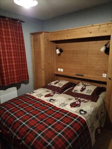 une chambre avec un lit avec une couverture à carreaux dans l'établissement Le hameau des Rennes, à Vars
